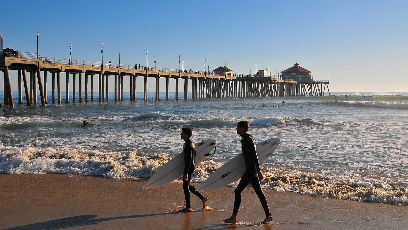 surfers walking with surfboards at huntington beach