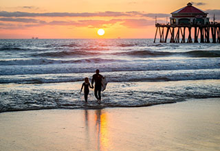 surfers walking into the ocean during sunset