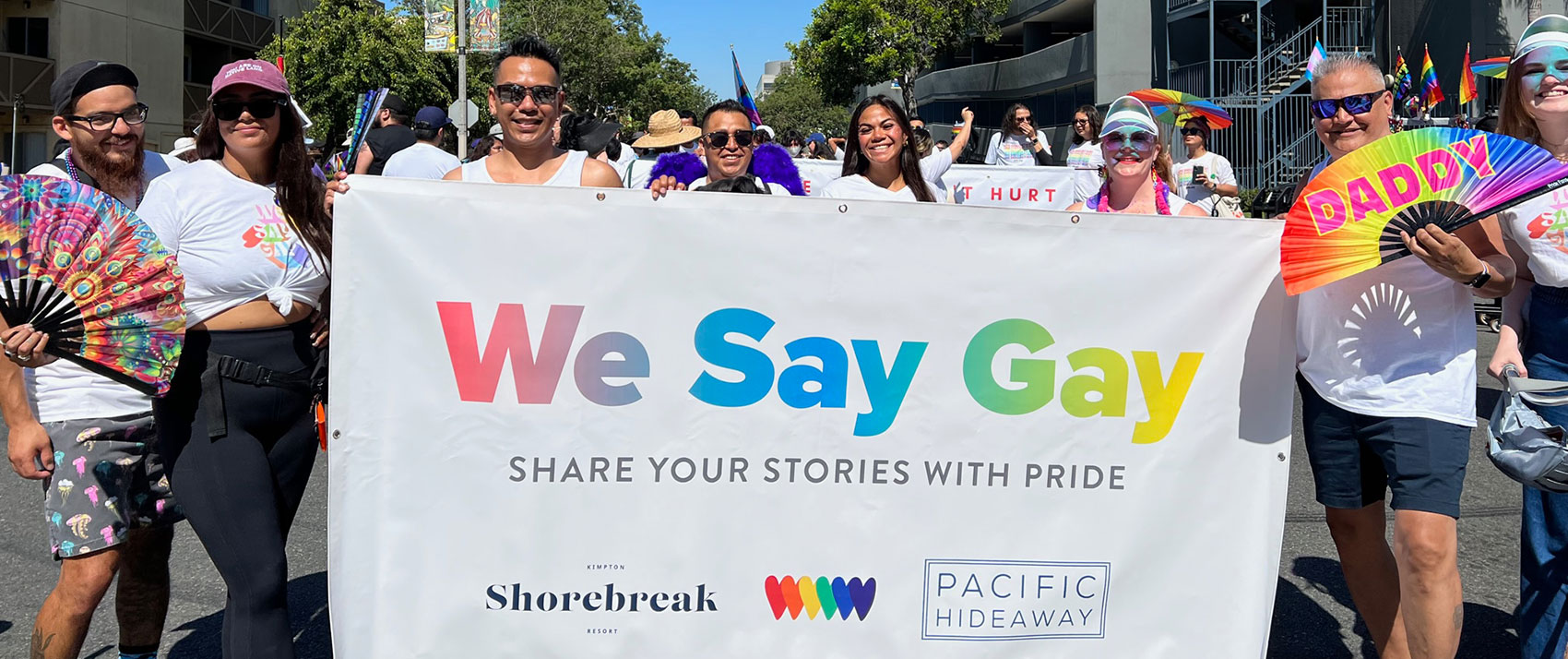 Pride Parade attendees with Shorebreak Pride banner that says We Say Gay - Share Your Stories with Pride
